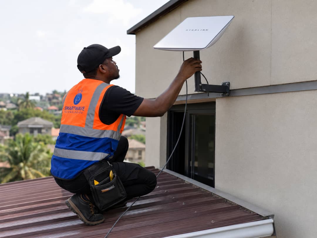 Smartwave technician in branded vest mounting a Starlink dish on a rooftop