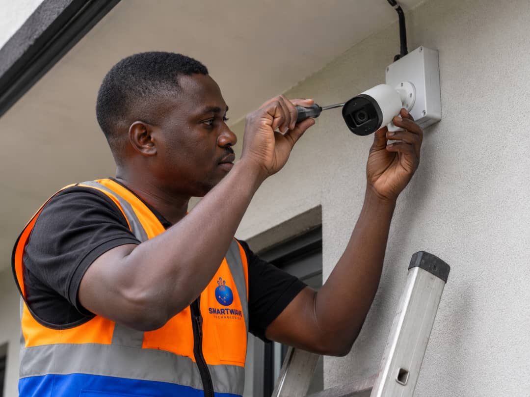 Smart Wave Technologies technician installing a CCTV camera on a building in Cameroon