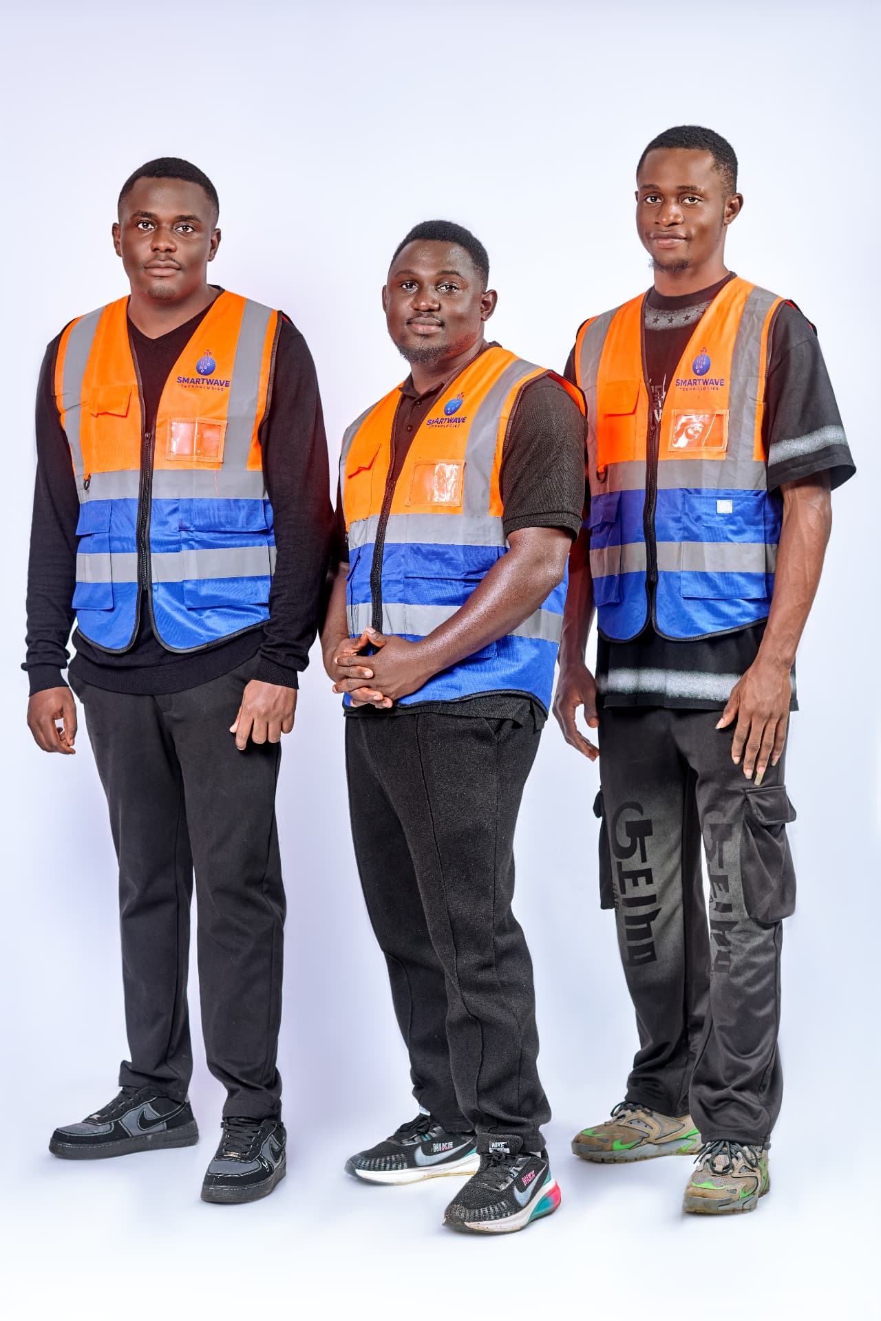 Three Smart Wave Technologies engineers in branded orange and blue safety vests